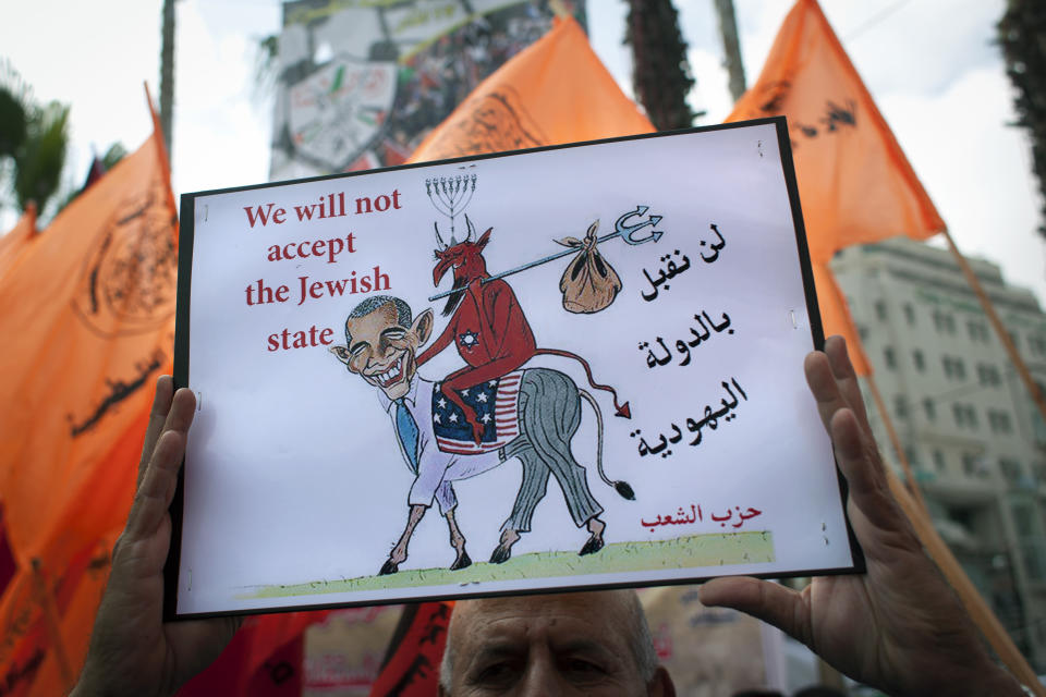 A Palestinian protester holds a placard with a drawing depicting U.S. President Barack Obama, during an anti-peace talks rally in the West Bank city of Ramallah, Wednesday, March 19, 2014. The Palestinians on Wednesday threatened to resume their campaign for international recognition at the United Nations if Israel calls off a planned release of Palestinian prisoners, deepening a crisis that has threatened to derail U.S.-led Mideast peace efforts. (AP Photo/Nasser Nasser)