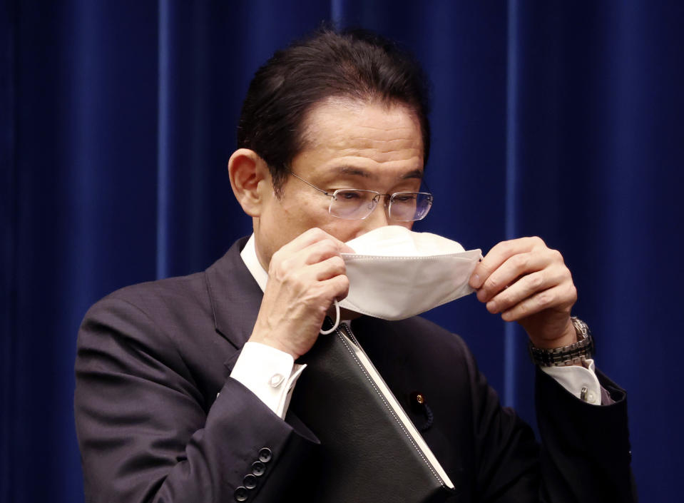 Japanese Prime Minister Fumio Kishida puts on a face mask as he leaves a press conference at the prime minister's official residence in Tokyo Tuesday, Dec. 21, 2021, as an extraordinary Diet session was closed on Tuesday. Japan’s parliament on Monday approved a record extra budget of nearly 36 trillion yen ($317 billion) for the fiscal year through March to help out pandemic-hit households and businesses.(Yoshikazu Tsuno/Pool Photo via AP)