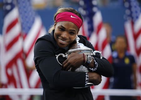 Serena Williams of the U.S. embraces her trophy after defeating Caroline Wozniacki of Denmark in their women's singles finals match at the 2014 U.S. Open tennis tournament in New York, in this September 7, 2014 file photo. REUTERS/Eduardo Munoz/Files