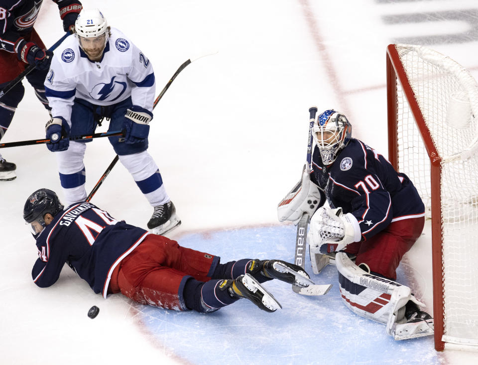 Columbus Blue Jackets defenseman Vladislav Gavrikov (44) goes down in front of goaltender Joonas Korpisalo (70) as Tampa Bay Lightning center Brayden Point (21) watches the puck during the third period in Game 4 of an NHL hockey first-round playoff series in Toronto on Monday, Aug. 17, 2020. (Frank Gunn/The Canadian Press via AP)