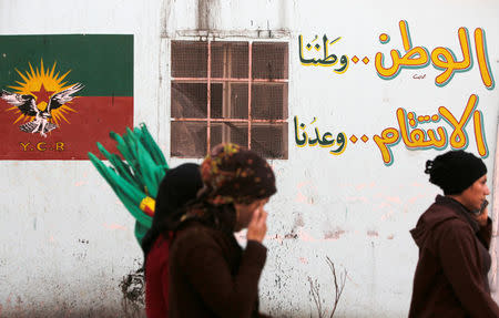 People walk next to a wall writing in the Sheikh Maksoud neighbourhood of Aleppo, Syria February 7, 2018. REUTERS/Omar Sanadiki