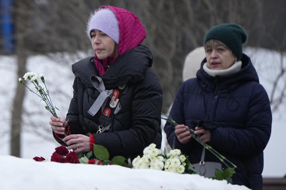 Women lay flowers to pay tribute to Alexei Navalny at the monument, a large boulder from the Solovetsky islands, where the first camp of the Gulag political prison system was established, near the historical Federal Security Service (FSB, Soviet KGB successor) building in Moscow, Russia, on Saturday, Feb. 24, 2024. Navalny, 47, Russia’s most well-known opposition politician, unexpectedly died on Feb. 16 in the penal colony, prompting hundreds of Russians across the country to stream to impromptu memorials with flowers and candles. (AP Photo/Alexander Zemlianichenko)