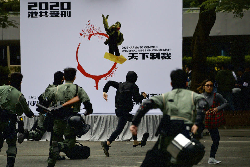 Riot police chase a masked man ahead of a rally demanding electoral democracy and call for boycott of the Chinese Communist Party and all businesses seen to support it in Hong Kong, Sunday, Jan. 19, 2020. Hong Kong has been wracked by often violent anti-government protests since June, although they have diminished considerably in scale following a landslide win by opposition candidates in races for district councilors late last year. (AP Photo/Ng Han Guan)