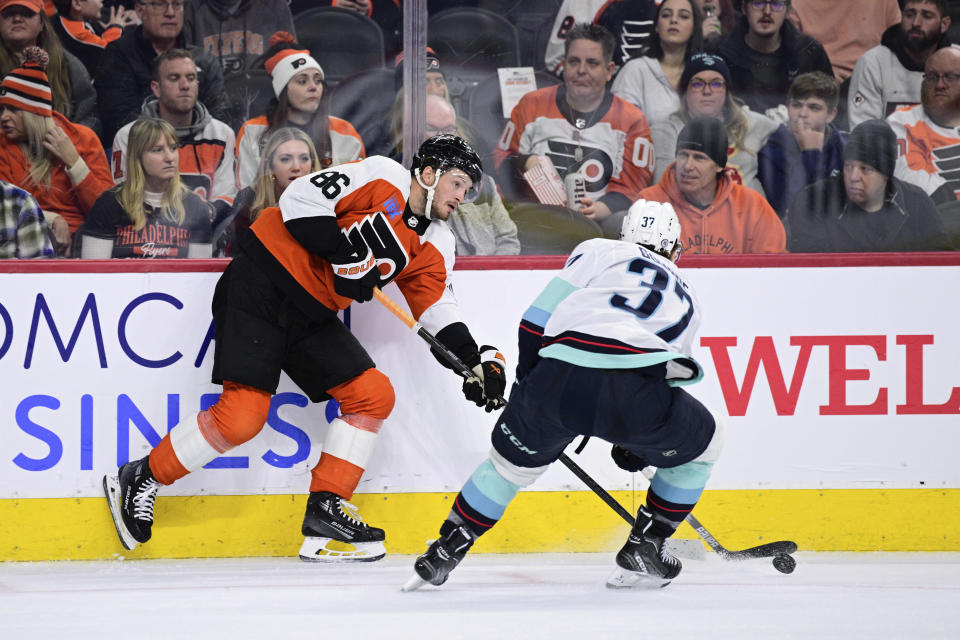 Philadelphia Flyers' Joel Farabee, left, passes the puck past Seattle Kraken's Yanni Gourde (37) during the second period of an NHL hockey game Saturday, Feb. 10, 2024, in Philadelphia. (AP Photo/Derik Hamilton)