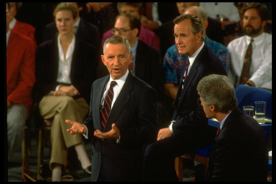 Three men in suits talking with each other while standing.