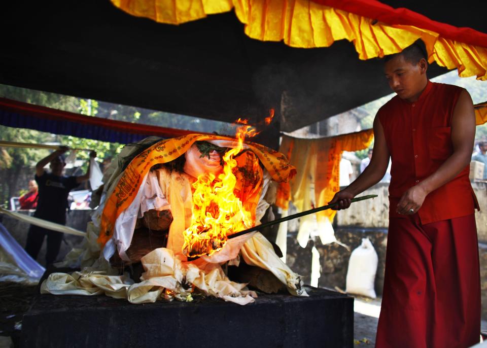 A Buddhist monk lights the funeral pyre of Nepalese climber Ang Kaji Sherpa killed in an avalanche on Mount Everest, in Katmandu, Nepal, Monday, April 21, 2014. (AP Photo/Niranjan Shrestha)