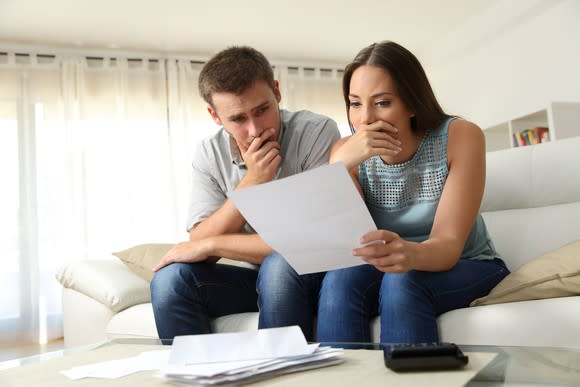 A couple looking at a bill with worried expressions