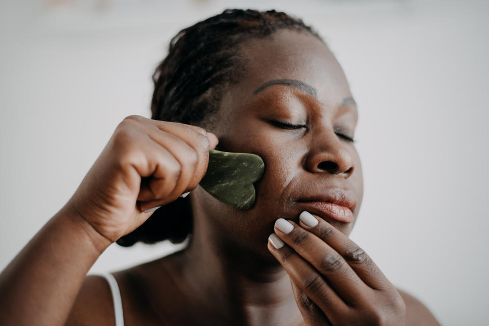 Mature woman using gua sha on face