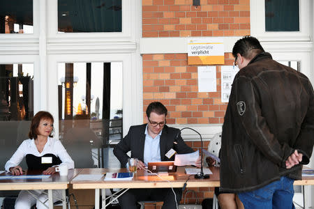 Election staff process a voter arriving at a polling place for the European elections, at the Kurhaus in Scheveningen, Netherlands May 23, 2019. REUTERS/Piroschka van de Wouw