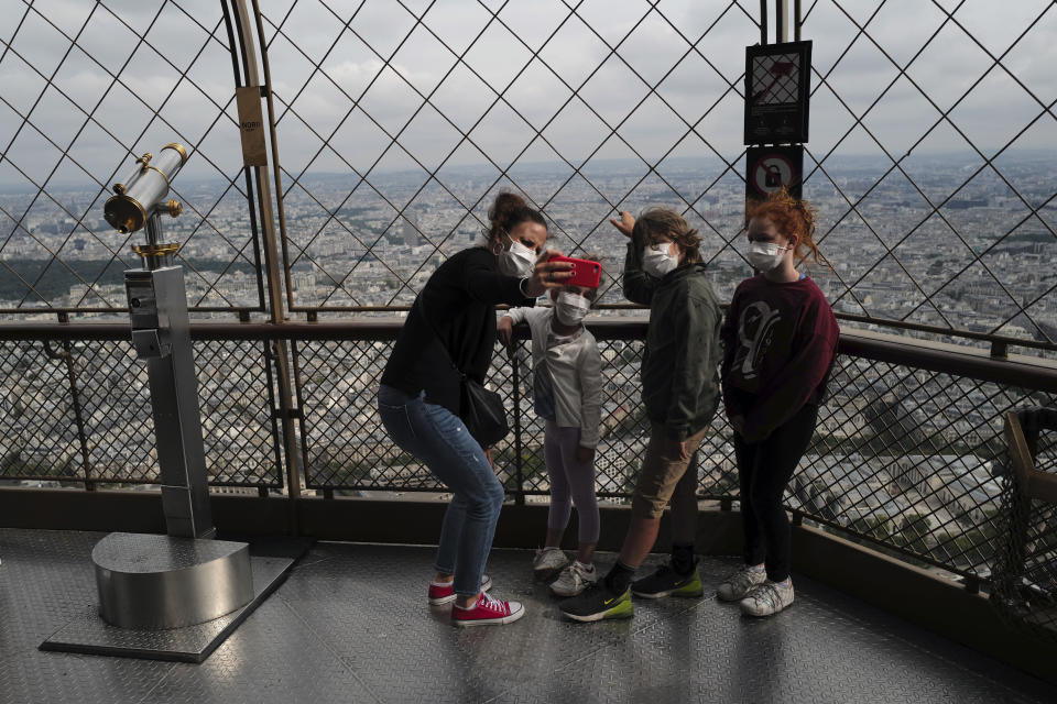 French visitors from south of France, Caroline, left, with her kids, Oxane, Rafaelle and Emma, from left to right, take a selfie from the third level during the opening up of the top floor of the Eiffel Tower, Wednesday, July 15, 2020 in Paris. The top floor of Paris' Eiffel Tower reopened today as the 19th century iron monument re-opened its first two floors on June 26 following its longest closure since World War II. (AP Photo/Francois Mori)