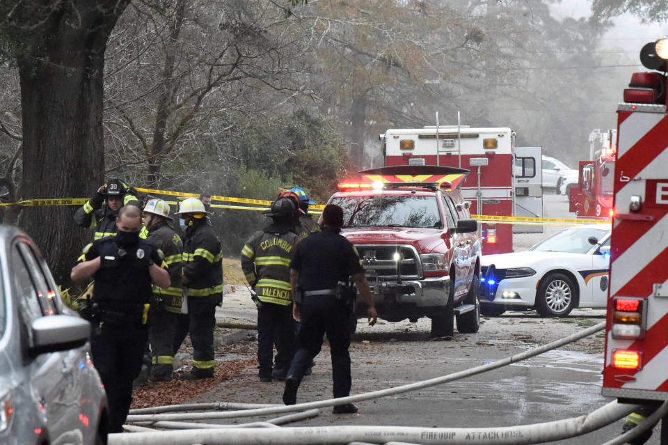 Officials clean up the scene following a small plane crash during dense fog in a residential neighborhood on Wednesday, Jan. 13, 2021, in Columbia, S.C. Authorities say the woman in the home was able to get out safely and have not given information on the condition of anyone aboard the plane. (AP Photo/Meg Kinnard)