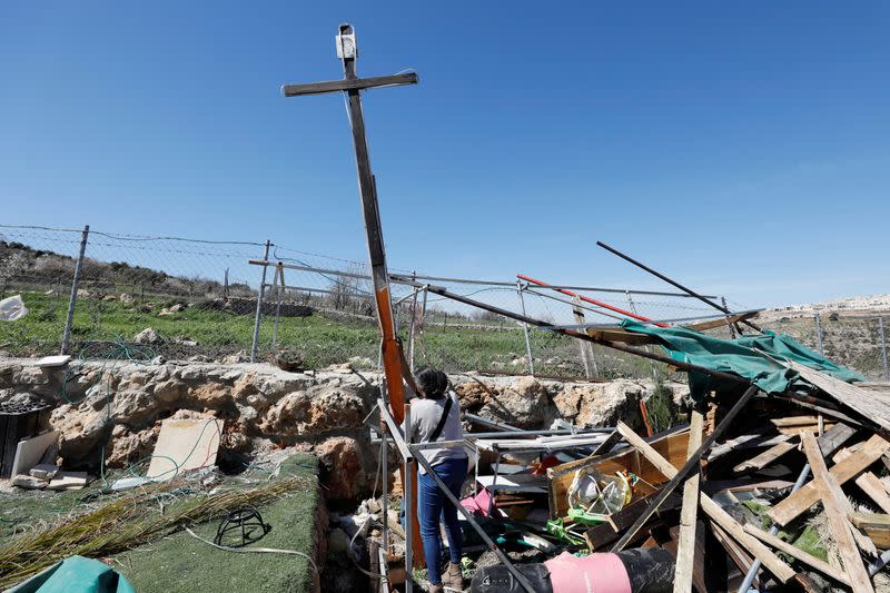 A Palestinian woman retrieves a wooden cross after an Israeli machinery bulldozed a land in the town of Beit Jala, in the Israeli-occupied West Bank