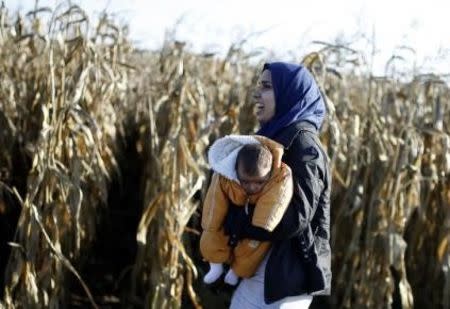 A migrant carrying a child passes beside a cornfield as she walks to cross the border into Croatia, near Sid, Serbia, October 2, 2015. REUTERS/Dado Ruvic