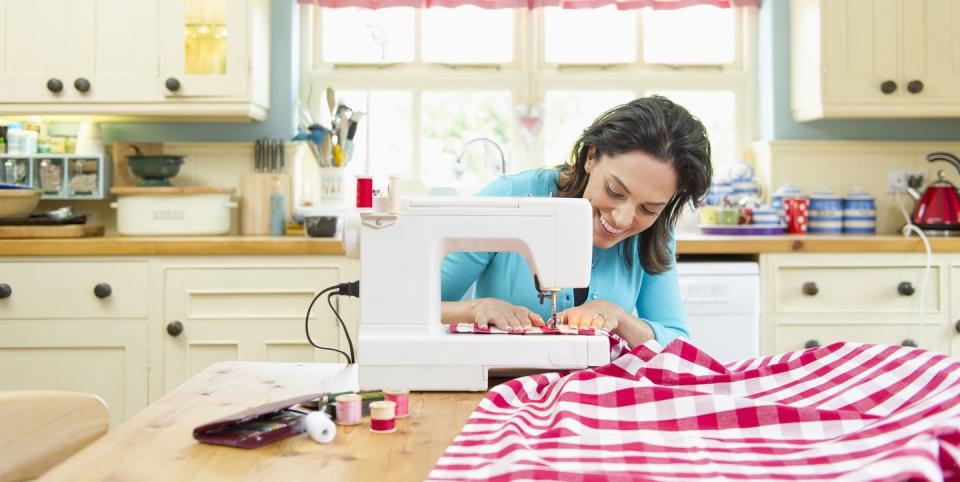 hispanic woman using sewing machine on kitchen table