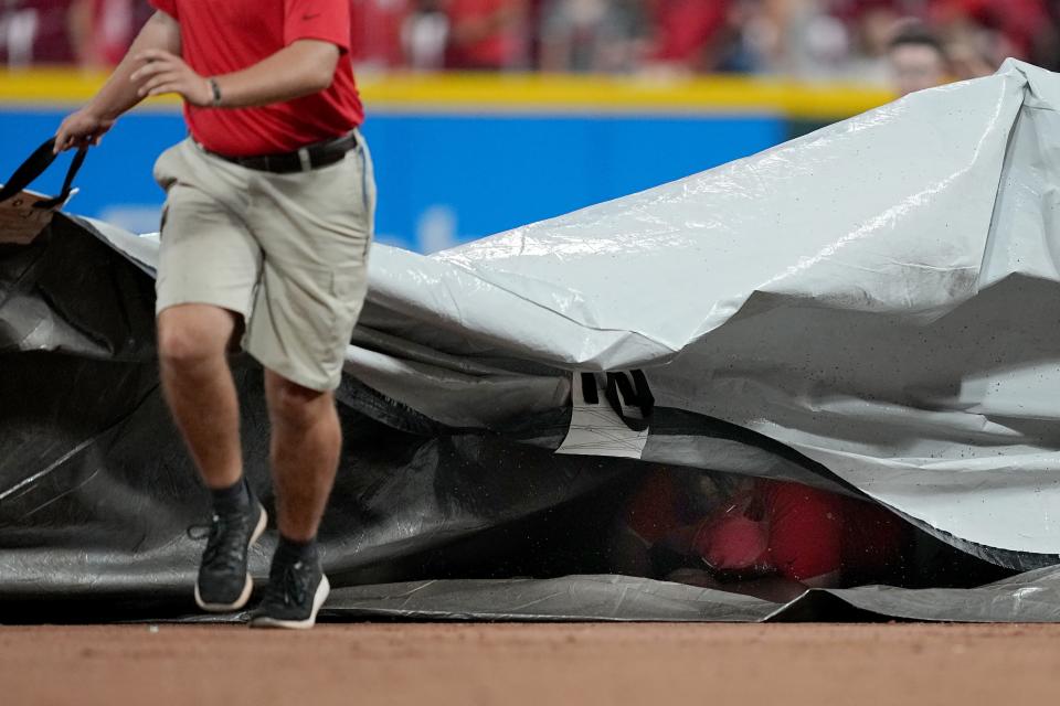 A member of the grounds crew falls underneath the tarp during a weather delay during the game between the San Francisco Giants and the Cincinnati Reds at Great American Ball Park.