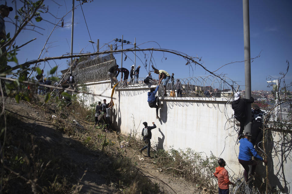 People climb a fence in the area at the border of Morocco and Spain, outside the Spanish enclave of Ceuta, Tuesday, May 18, 2021. (AP Photo/Mosa'ab Elshamy)