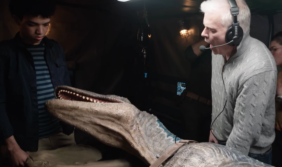 Star Wars creature expert Neal Scanlan operates an animatronic dinosaur as Justice Smith looks on in awe (Universal Pictures)