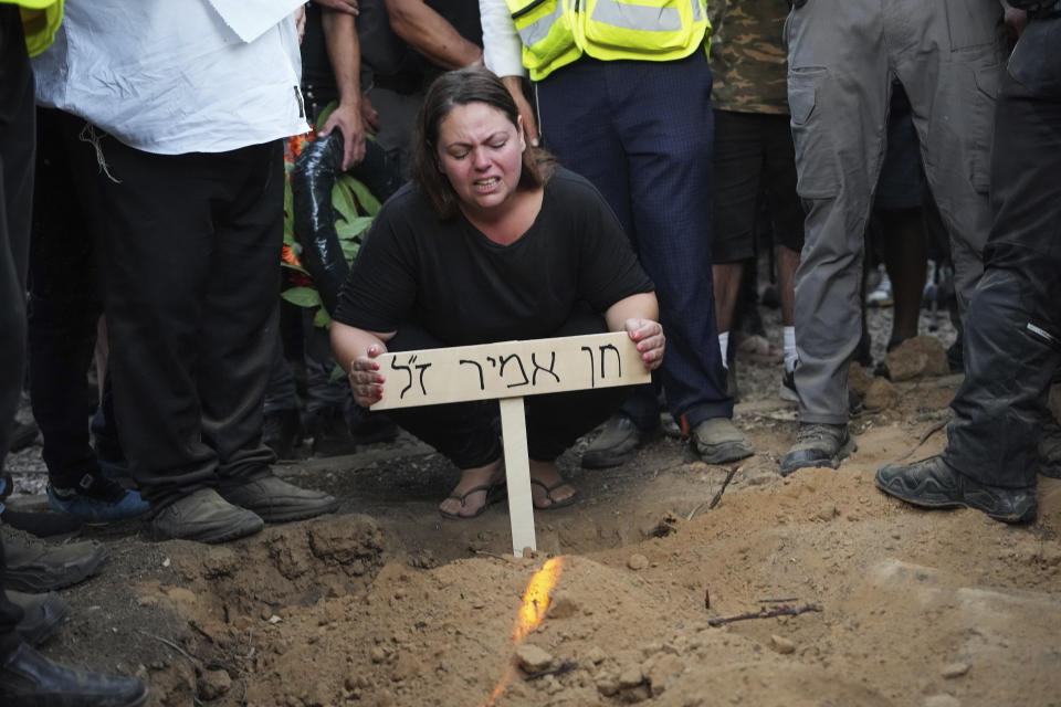 Wife of Chen Amir mourns over his grave, during his funeral in Kibbutz Re'im, Israel, Sunday, Aug 6, 2023. On Saturday a Palestinian gunman shot and killed Amir, 42, an Israeli security guard in central Tel Aviv. The attacker was shot and killed. (AP Photo/Tsafrir Abayov)