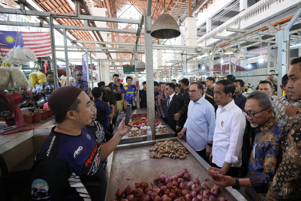 Indonesian President Joko Widodo, third right, talks with a local vendor with Malaysian Prime Minister Anwar Ibrahim, fourth right, as they visit a local wet market in Kuala Lumpur, Malaysia, Thursday, June 8, 2023. (AP Photo/Vincent Thian)