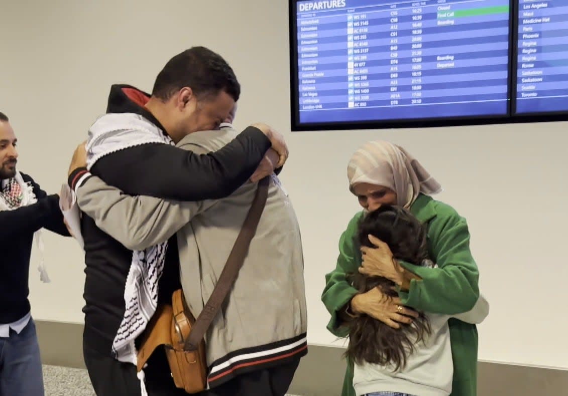 Ossama Zaqqout, left, embraces his father at the Calgary International Airport on Saturday, April 28. His Mother, right, hugs another family member.  (Terri Trembath/CBC - image credit)