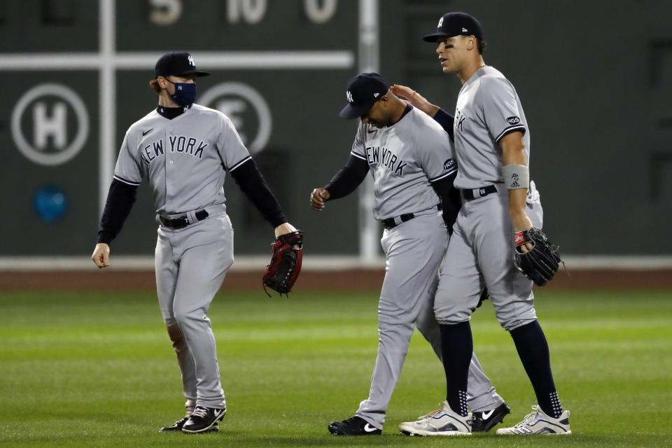 New York Yankees' Clint Frazier, left, Aaron Hicks, center, and Aaron Judge celebrate after the Yankees defeated the Boston Red Sox in the 12th inning of a baseball game, early Saturday, Sept. 19, 2020, in Boston. (AP Photo/Michael Dwyer)