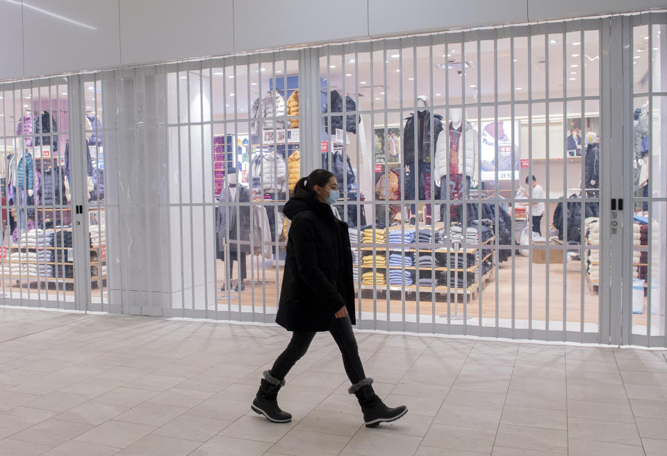 A woman walks by a closed store in a shopping mall in Montreal, Sunday, Jan. 2, 2022, as the COVID-19 pandemic continues in Canada. Some measures put in place by the Quebec government, including the closure of stores, go into effect today to help curb the spread of COVID-19 in the province. (Graham Hughes /The Canadian Press via AP)