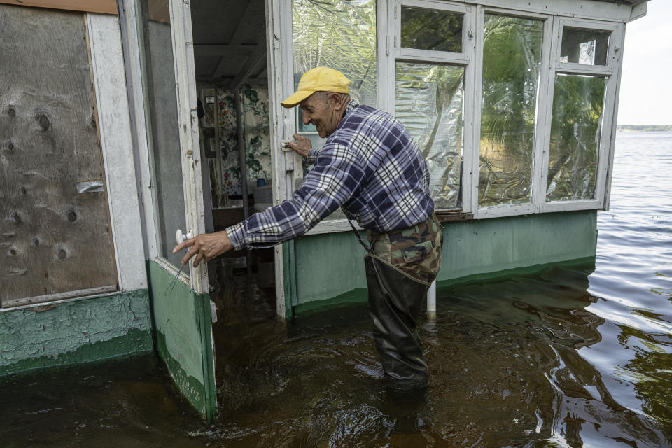 Mykola Gurzhiy, 74, a local fisherman opens a door of his flooded house in the island of Kakhovka reservoir on Dnipro river near Lysohirka, Ukraine, Thursday, May 18, 2023. Damage that has gone unrepaired for months at a Russian-occupied dam is causing dangerously high water levels along a reservoir in southern Ukraine. (AP Photo/Evgeniy Maloletka)