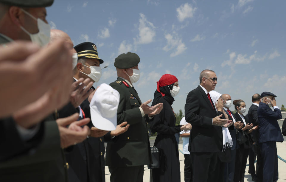 Turkey's President Recep Tayyip Erdogan, center, and family members of coup victims pray at the "Martyrs Monument" outside his presidential palace, in Ankara, Turkey, Wednesday, July 15, 2020. Turkey is marking the fourth anniversary of the July 15 failed coup attempt against the government, with prayers and other events remembering its victims.(Turkish Presidency via AP, Pool)