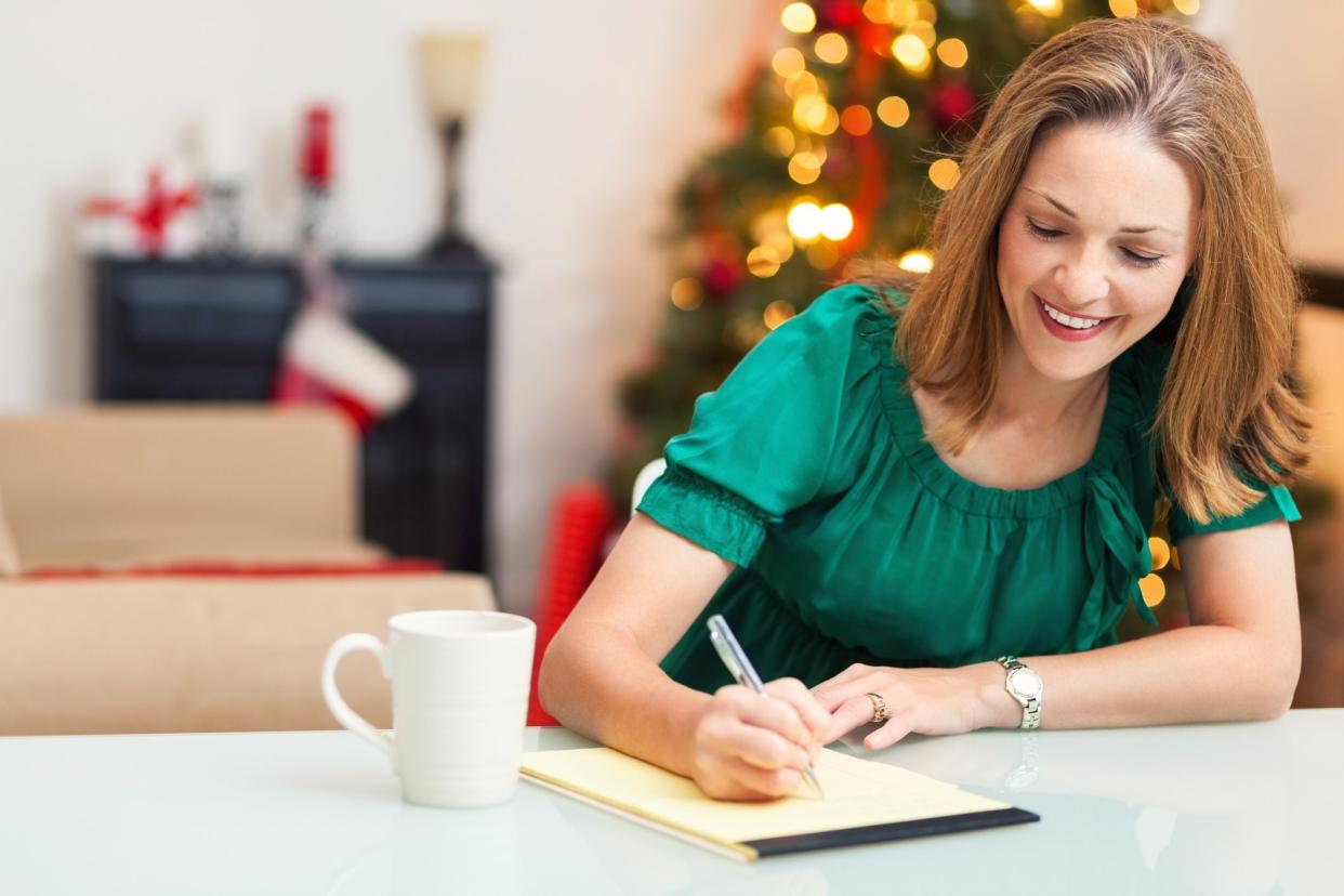 woman writing list with christmas tree in background