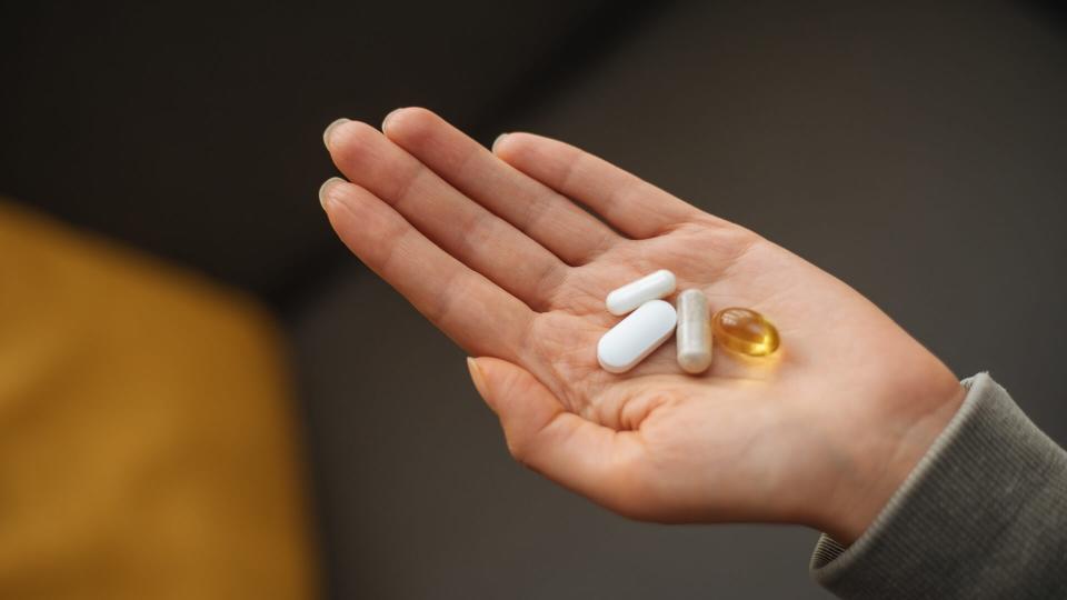 A hand holding a bunch of pills in an open palm.