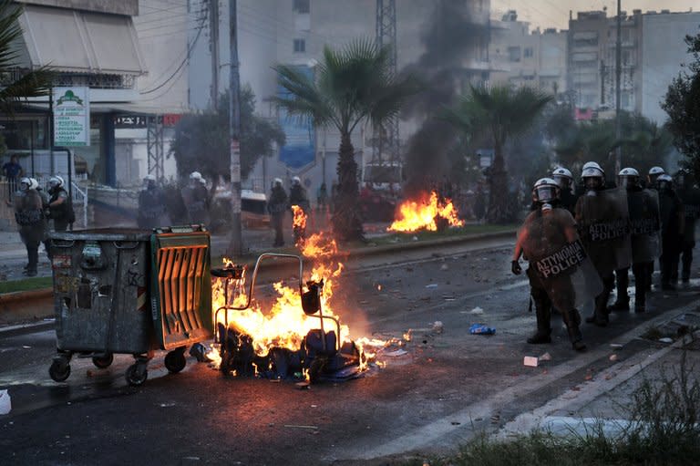 Riot police stand beside burning barricades during clashes with anti-fascist protesters in the western Athens working class suburb of Keratsini on September 18, 2013. Greece's prime minister vowed to rein in the neo-Nazi Golden Dawn party after the murder of an anti-fascist singer by one of its supporters sparked nationwide outrage