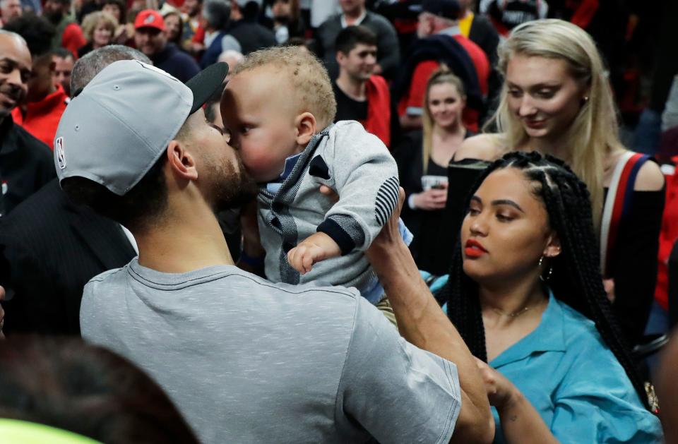 Golden State Warriors guard Stephen Curry, left, kisses his son Canon, as his wife Ayesha, lower right, looks on, at the end of Game 4 of the NBA basketball playoffs Western Conference finals against the Portland Trail Blazers, Monday, May 20, 2019, in Portland, Ore.