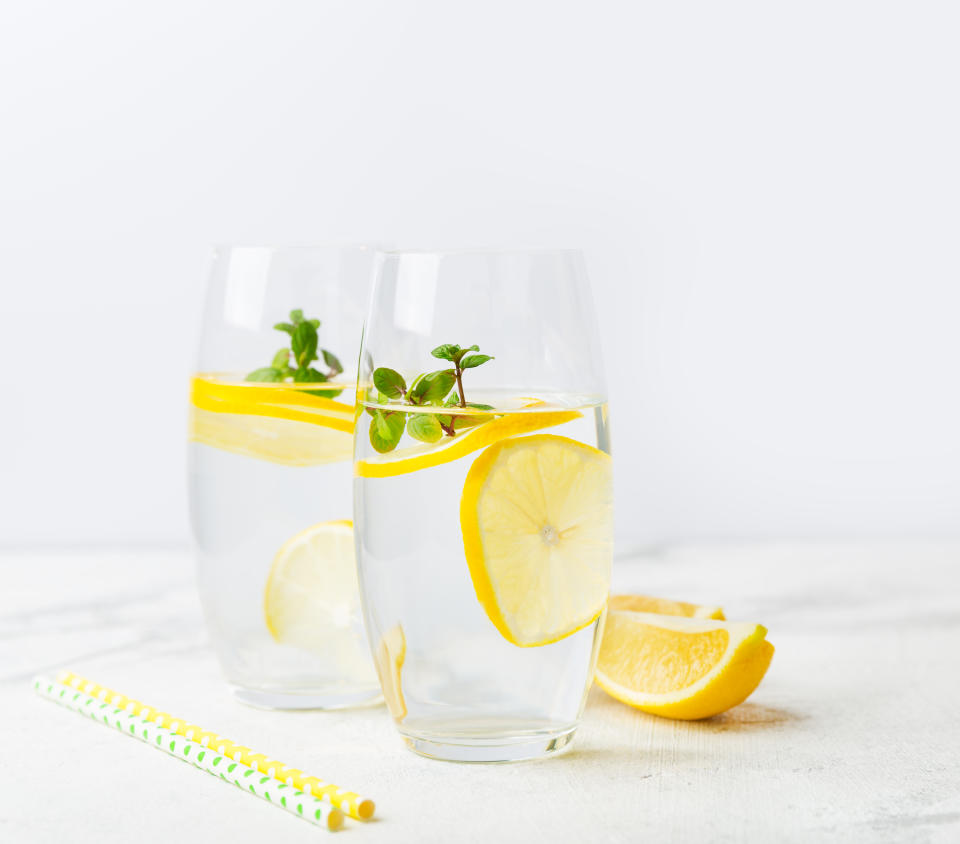 Two glasses of water with lemon, homemade refreshing lemonade with slices of organic ripe lemon. The concept of a healthy lifestyle, the right start to the day, a charge of vivacity. Close-up, copy space.�