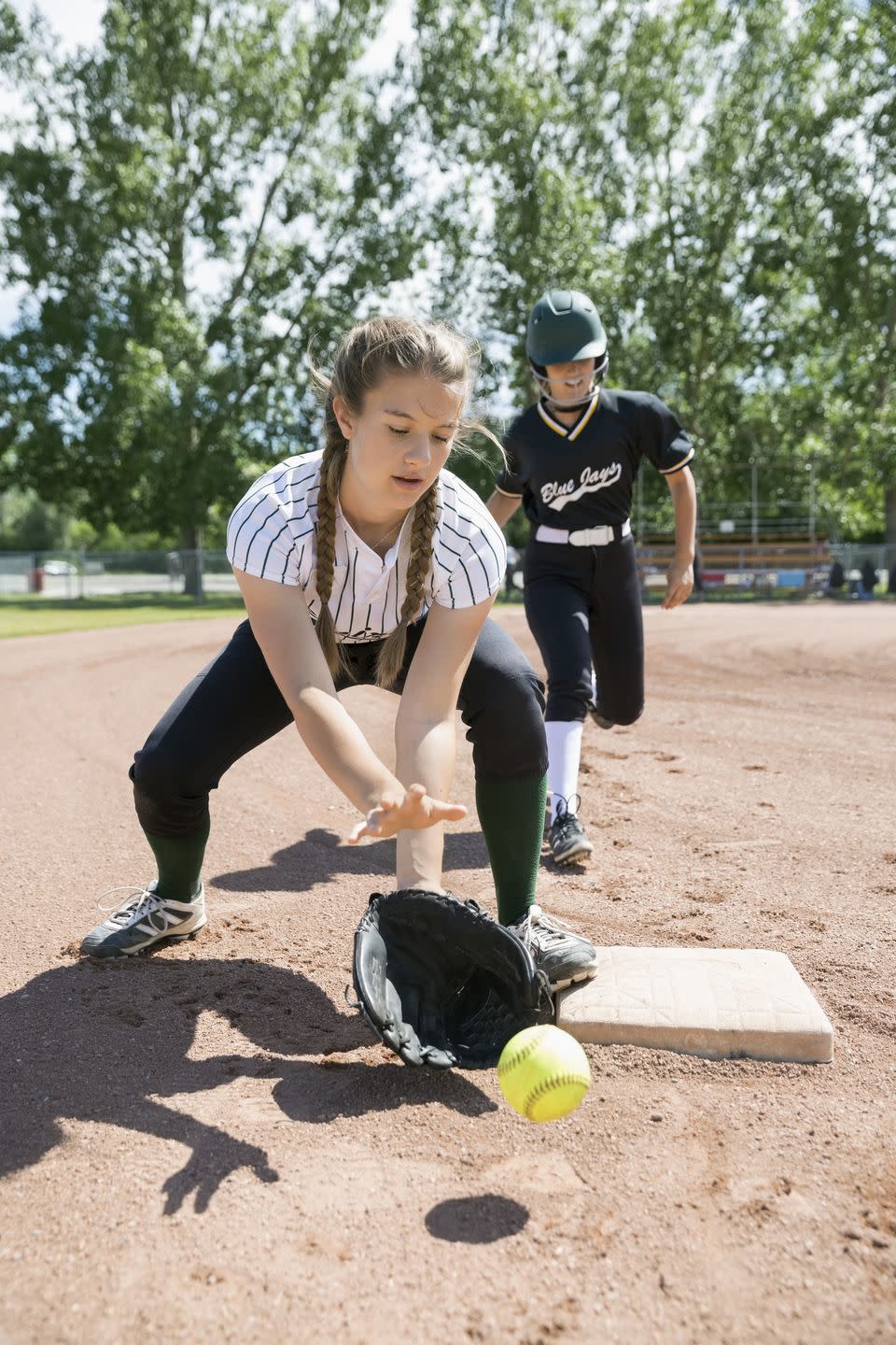 middle school girl softball player catching softball at base