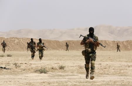 File photo of Asaib Ahl al-Haq Shi'ite militia fighters from the south of Iraq and Kurdish peshmerga forces walking with their weapons as they take control of Sulaiman Pek from the Islamist State militants, in the northwest of Tikrit city September 1, 2014. REUTERS/Youssef Boudlal