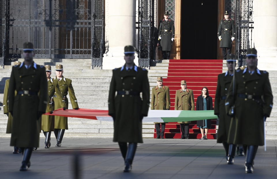 Hungarian President Katalin Novak, on carpet right, attends a flag-raising ceremony at the parliament building in Budapest, Hungary, Sunday, Oct. 23, 2022 to mark the 66th anniversary of the outbreak of the Hungarian revolution and war of independence against communist rule and the Soviet Union in 1956. (Noemi Bruzak/MTI via AP)