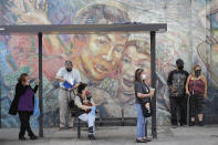 People wear masks as they wait at a bus stop amid the coronavirus pandemic Monday, June 29, 2020, in Los Angeles. (AP Photo/Marcio Jose Sanchez)