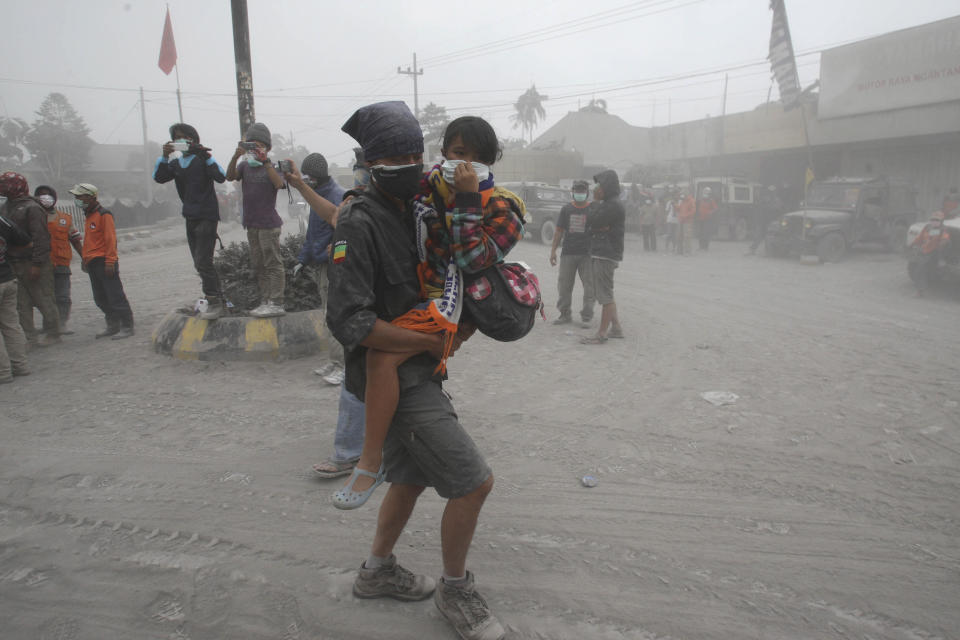 A rescuer carries a child to a truck for evacuation following an eruption of Mount Kelud, in Malang, East Java, Indonesia, Saturday, Feb. 15, 2014. The powerful volcanic eruption on Indonesia's most populous island blasted ash and debris 18 kilometers (12 miles) into the air Friday, forcing authorities to evacuate more than 100,000 and close seven airports. (AP Photo/Trisnadi)