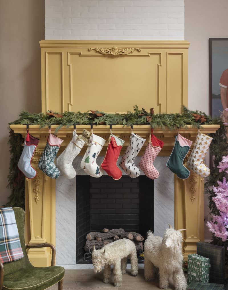 Stockings hang on a yellow fireplace in the living room.