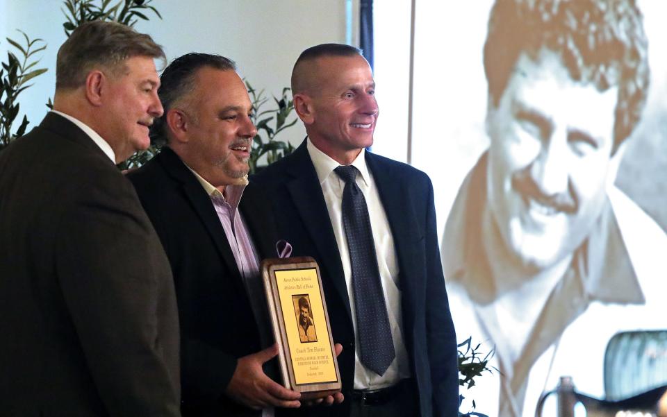 A portrait of Akron high school football legend Tim Flossie appears to watch as Joe Flossie, center, poses with Ron Linger and Joe Vassalotti after giving an acceptance speech on behalf of his father during the 2023 Akron Public Schools Athletics Hall of Fame induction ceremony Saturday at House Three Thirty in Akron.