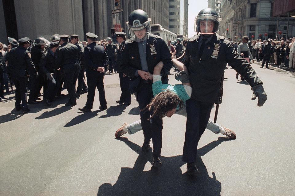 New York City police arrest a demonstrator during an Earth Day protest in morning, Monday, April 23, 1990, in New York in the Wall Street district. Police closed part of Wall Street to traffic and most pedestrians and arrested more than 170 demonstrators who staged a protest aimed at disrupting business in the financial center. (AP Photo/Osamu Honda)