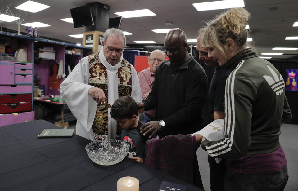 <p>Rev. Jerry Hogan, left, of the U.S. Conference of Catholic Bishops’ Circus and Traveling Shows Ministry, leads a baptism service for 6-year-old Eddie Strickland, the son of Jimmie Strickland, a member of the crew before a Ringling Bros. circus show at the Dunkin Donuts Center, Thursday, May 4, 2017, in Providence, R.I. Hogan’s vestments were made by the costume department from old elephant blankets. (Photo: Julie Jacobson/AP) </p>