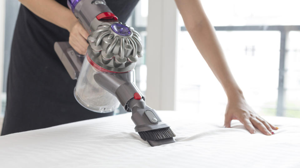 Cleaning a mattress with a handheld vacuum cleaner to get rid of dust mites