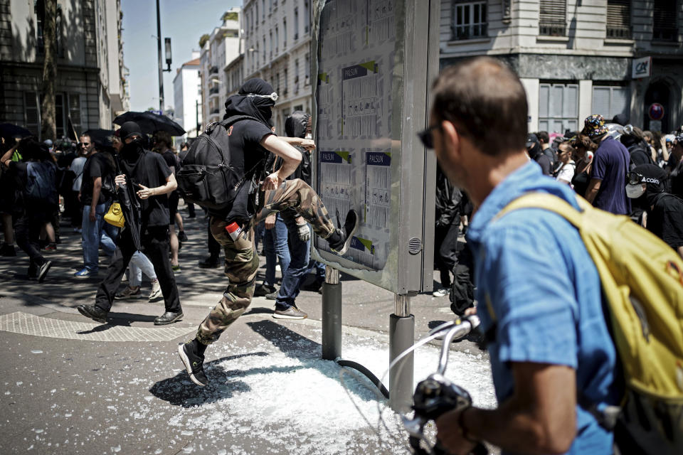 A man jumps to smash a billboard during a protest in Lyon, central France, Tuesday, June 6, 2023. French unions are seeking to reignite resistance to President Emmanuel Macron's higher retirement age with what may be a final surge of nationwide protests and scattered strikes Tuesday. (AP Photo/Laurent Cipriani)