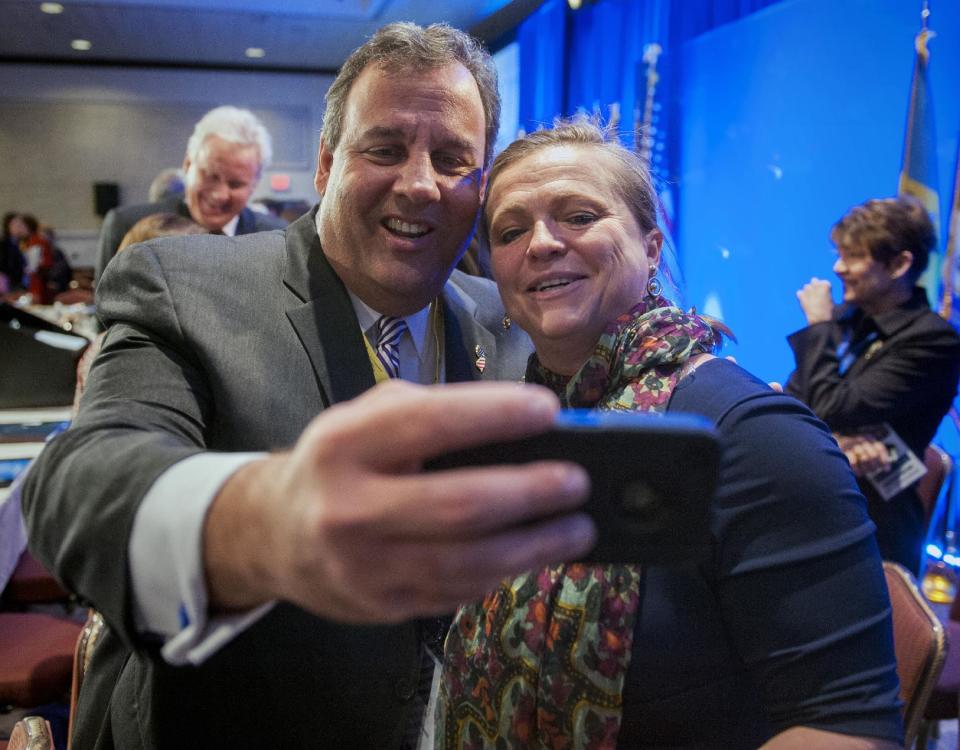 New Jersey Gov. Chris Christie takes a cell phone photo with NGA staffer Lily Kersh during the National Governor's Association Winter Meeting in Washington, Saturday, Feb. 22, 2014. (AP Photo/Cliff Owen)