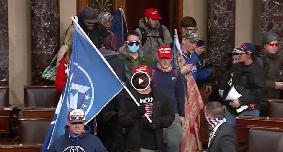 Chriss Carnell of Cary, (center and wearing a red cap) and David Bowman of Raleigh (center left in blue mask) were both arrested by the FBI this month on Jan.. 6-related felony and misdemeanor charges.