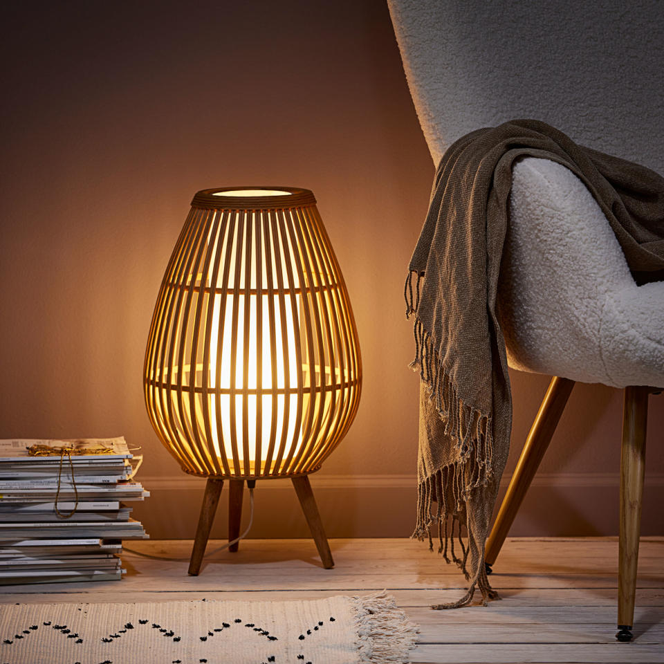 floor lamp casting diffused light beside an armchair draped with a cosy throw