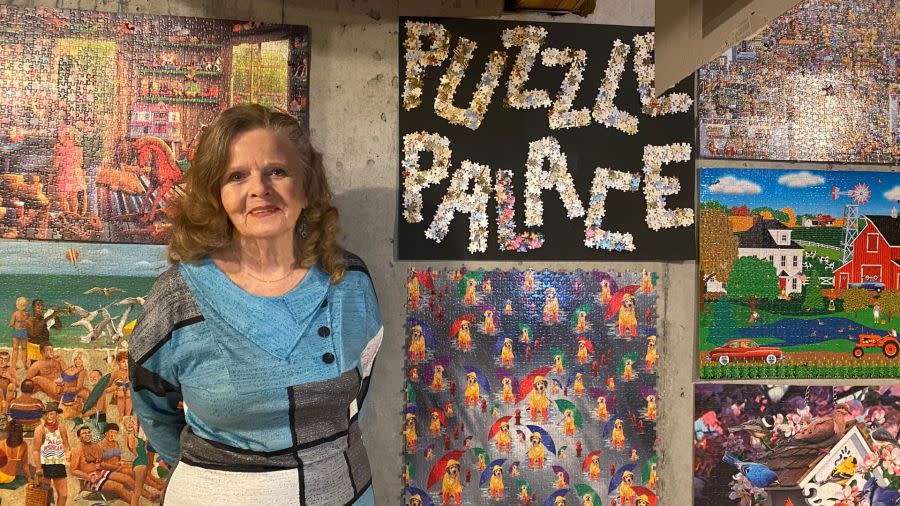 Barbara Lillis next to the sign she created using discarded puzzle pieces