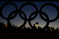 People watch the cauldron rise at sunset by the Olympic rings during the 2024 Summer Olympics, Monday, Aug. 5, 2024, in Paris, France. (AP Photo/Natacha Pisarenko)