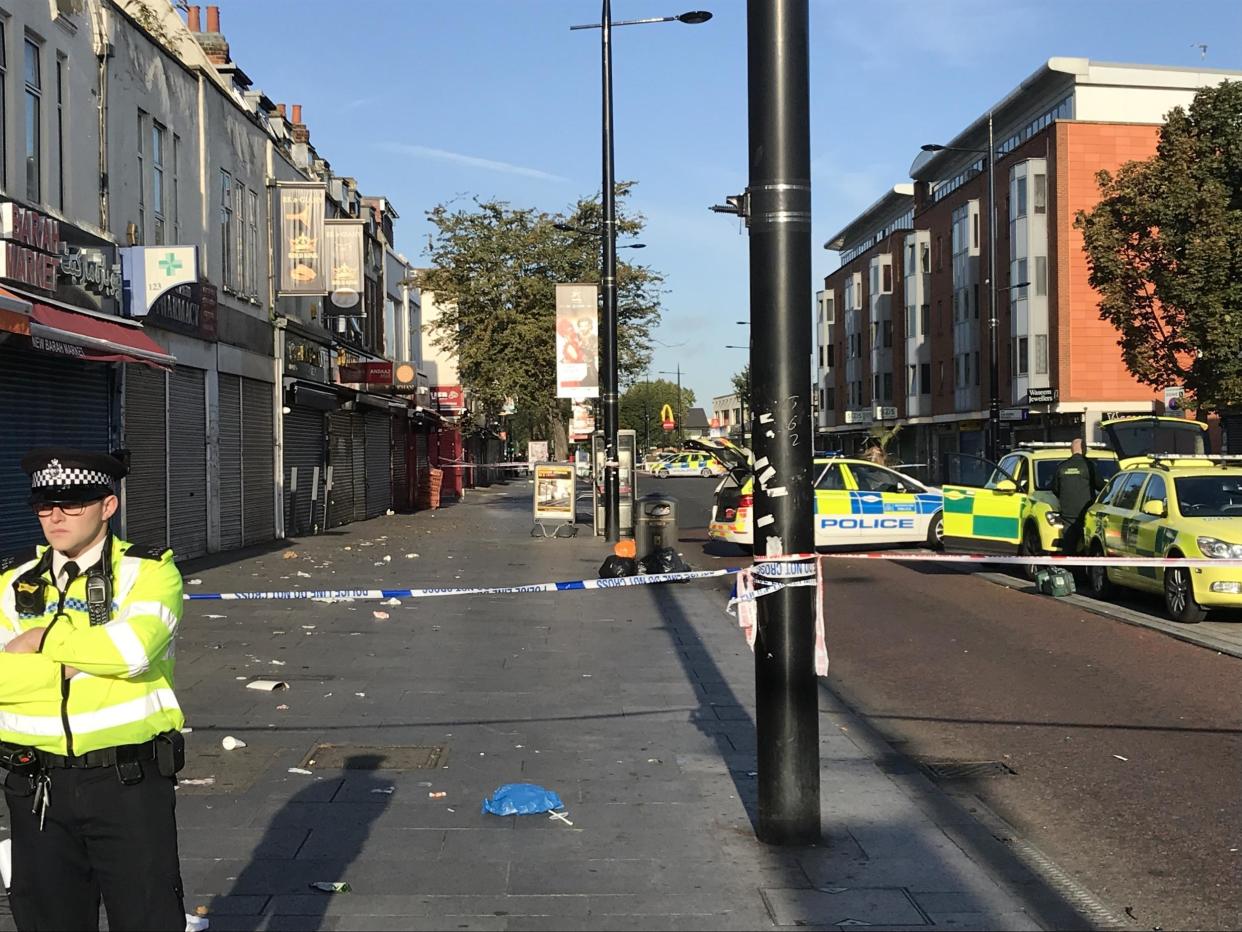 Police at the scene in Southall after a man was found injured outside a shop and later died